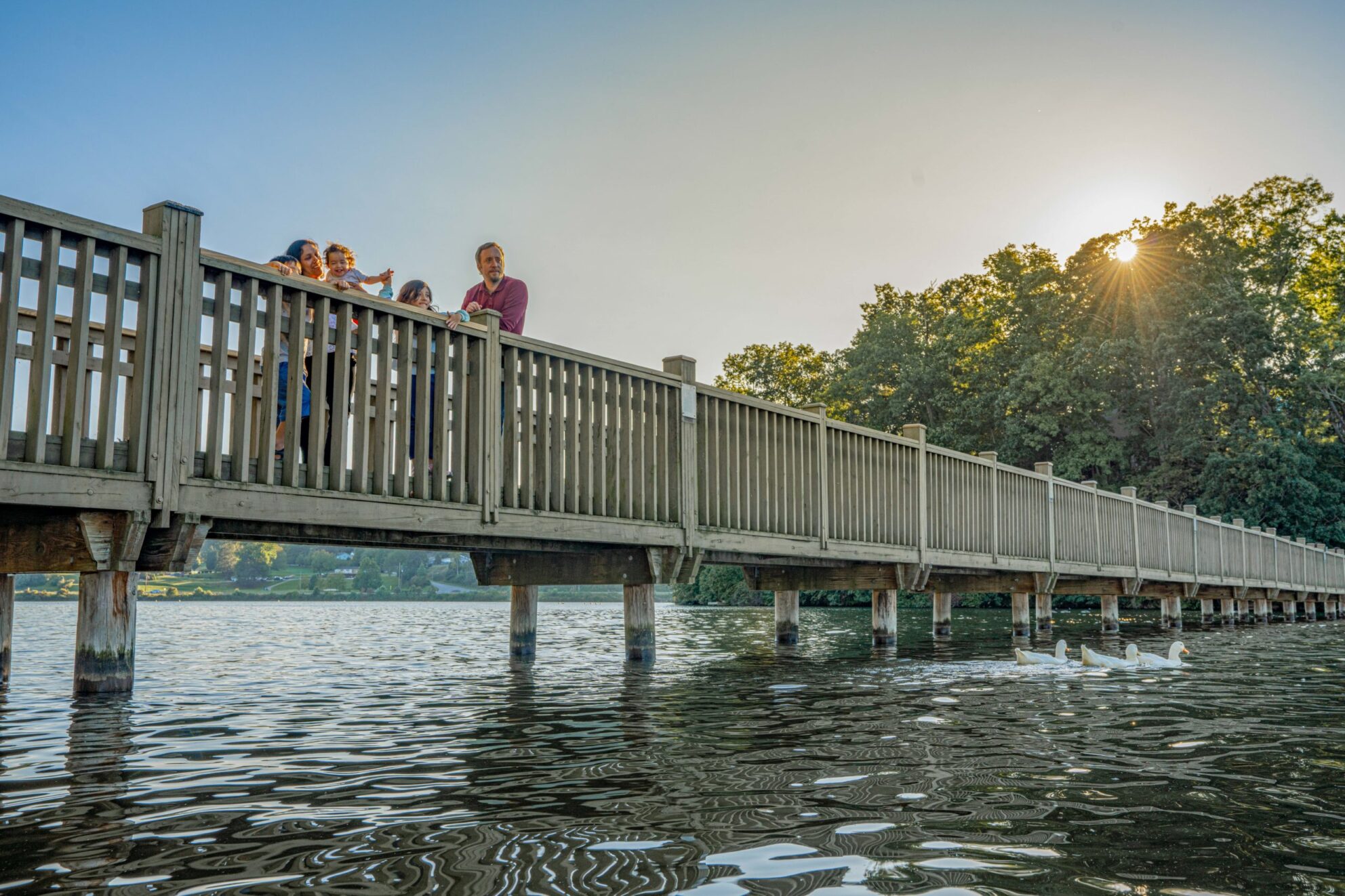 A family stands on the Lake Junaluska walking bridge and looks at the lake