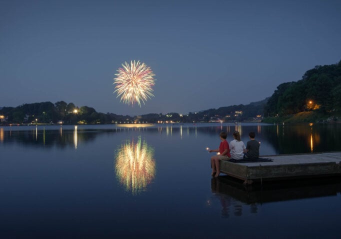 Fireworks over Lake Junaluska with kids sitting on a dock in the foreground