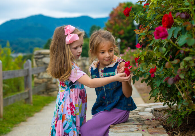 Two young girls looking at flowers on the Rose Walk trail at Lake Junaluska