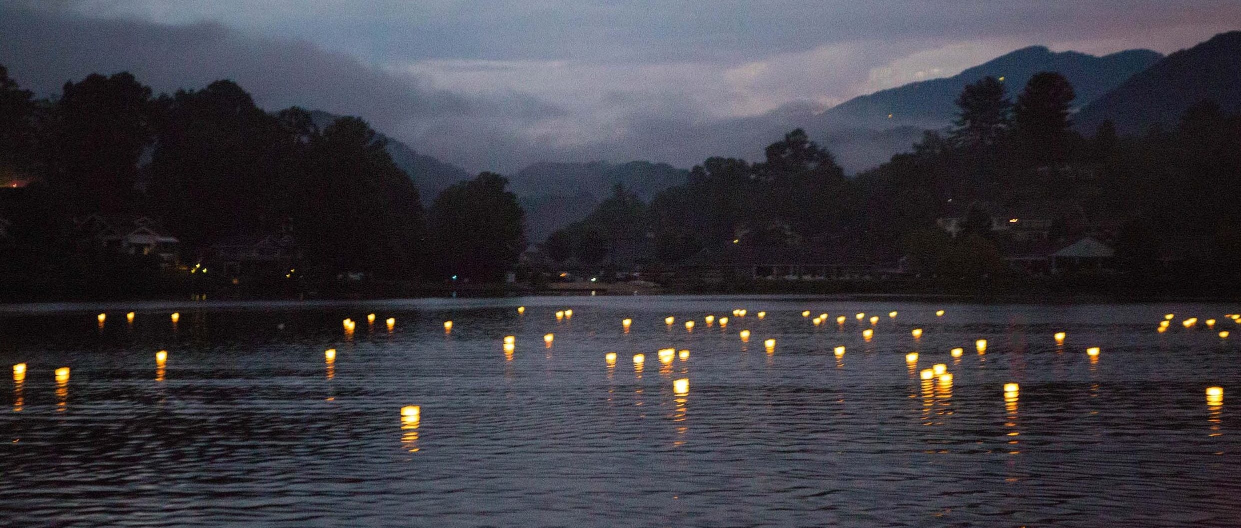 Floating wish lanterns cast glimmers of light on the water