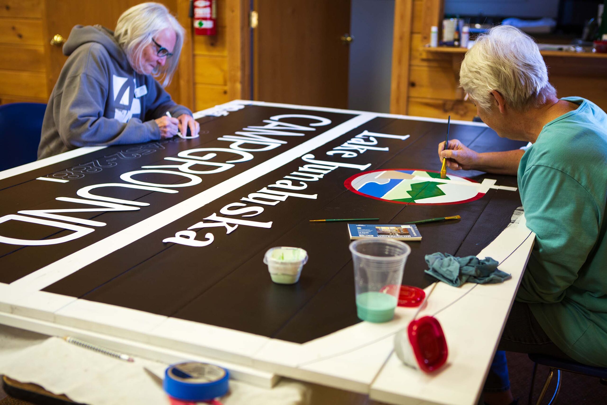 Volunteers paint a campground sign