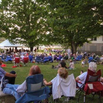 Visitors enjoy an outdoor concert at the lakeside tent