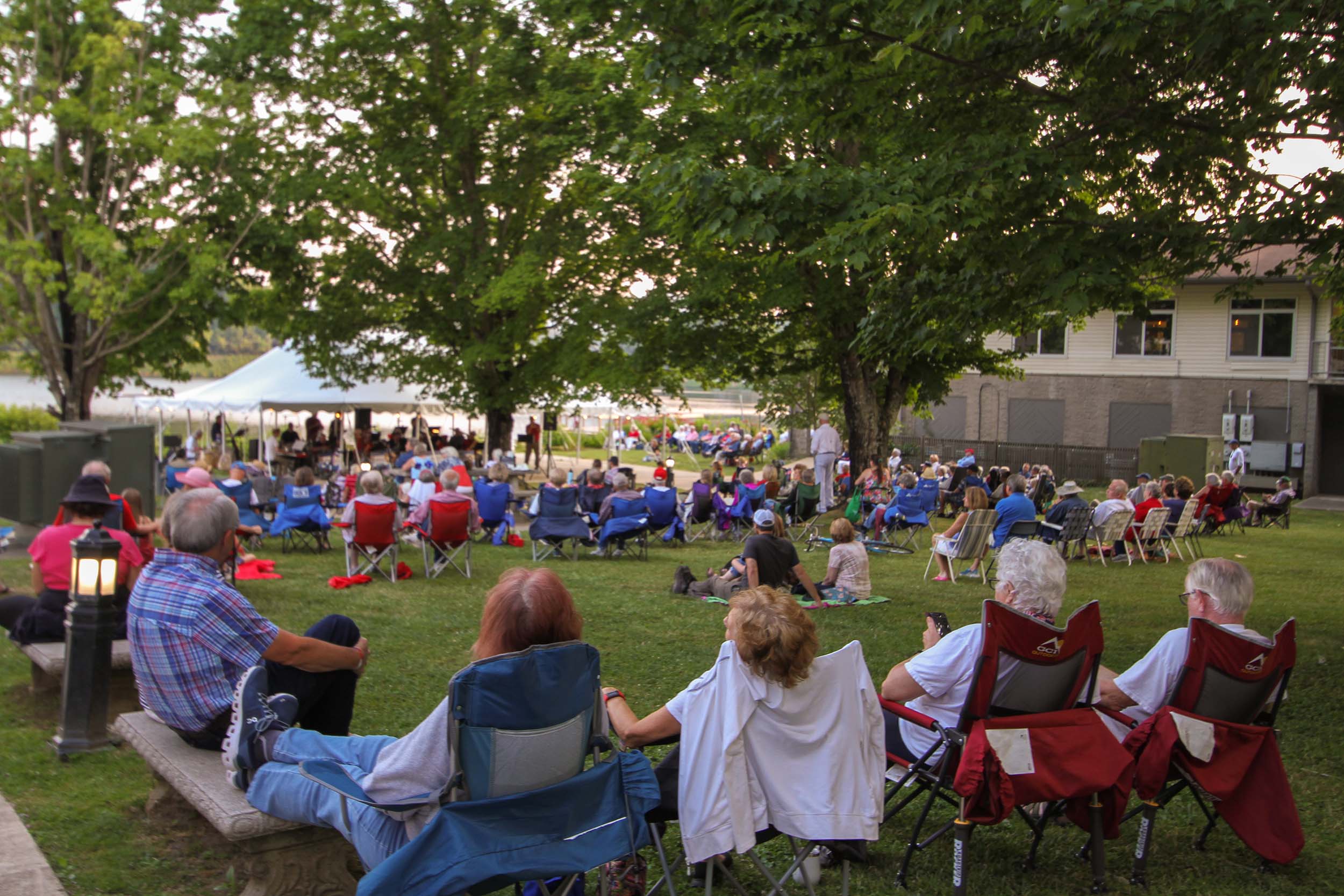 Visitors enjoy an outdoor concert at the lakeside tent